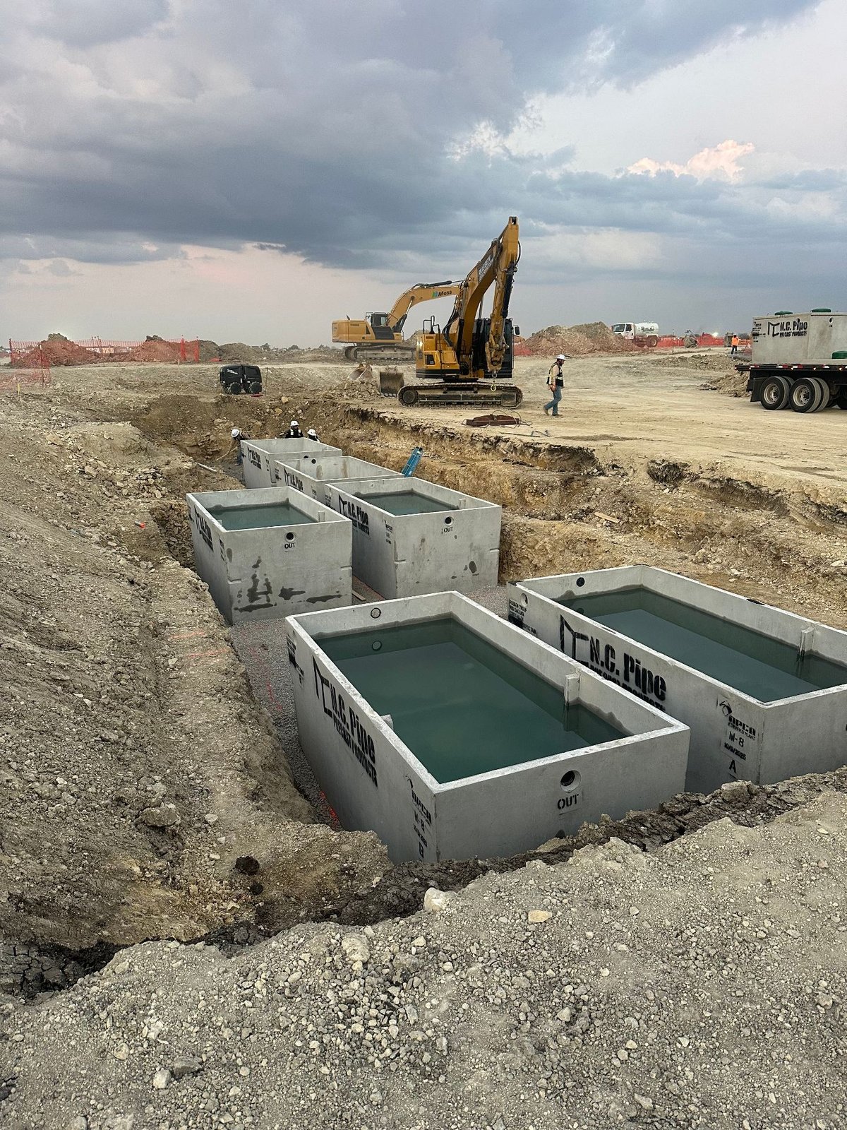 Precast concrete septic tanks set in open trench during commercial wastewater system installation