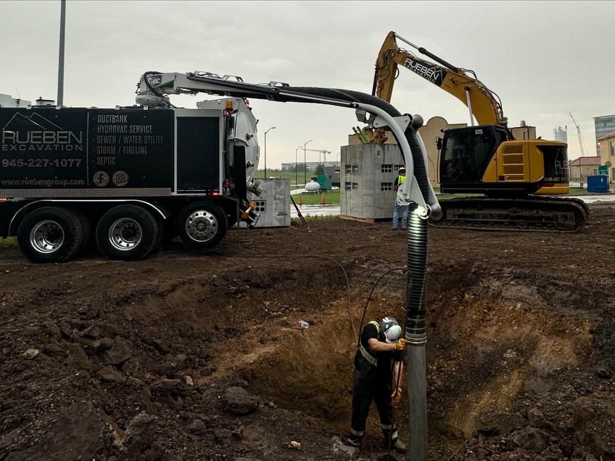 Rueben Excavation crew operating hydrovac wand exposing utilities in a deep excavation