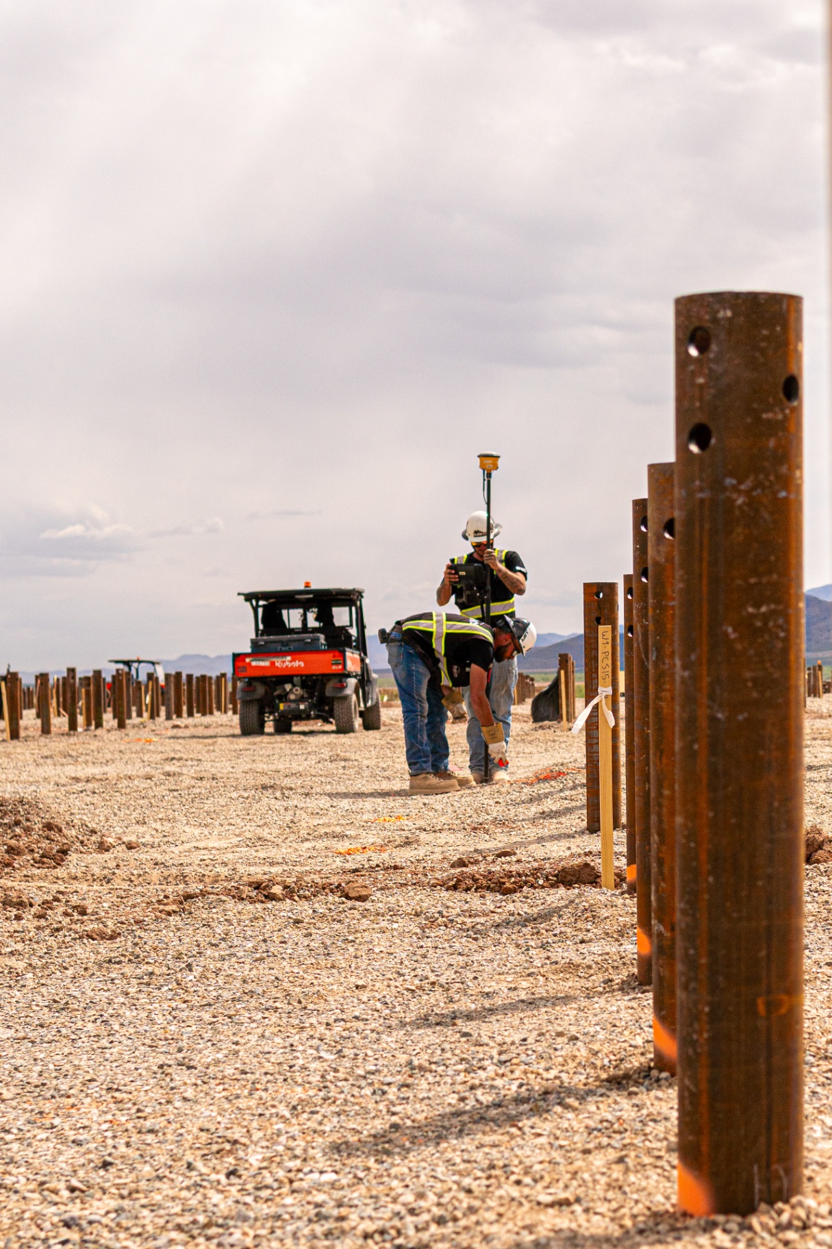 Rueben Excavation survey crew verifying helical pile layout with GPS rover on a solar site
