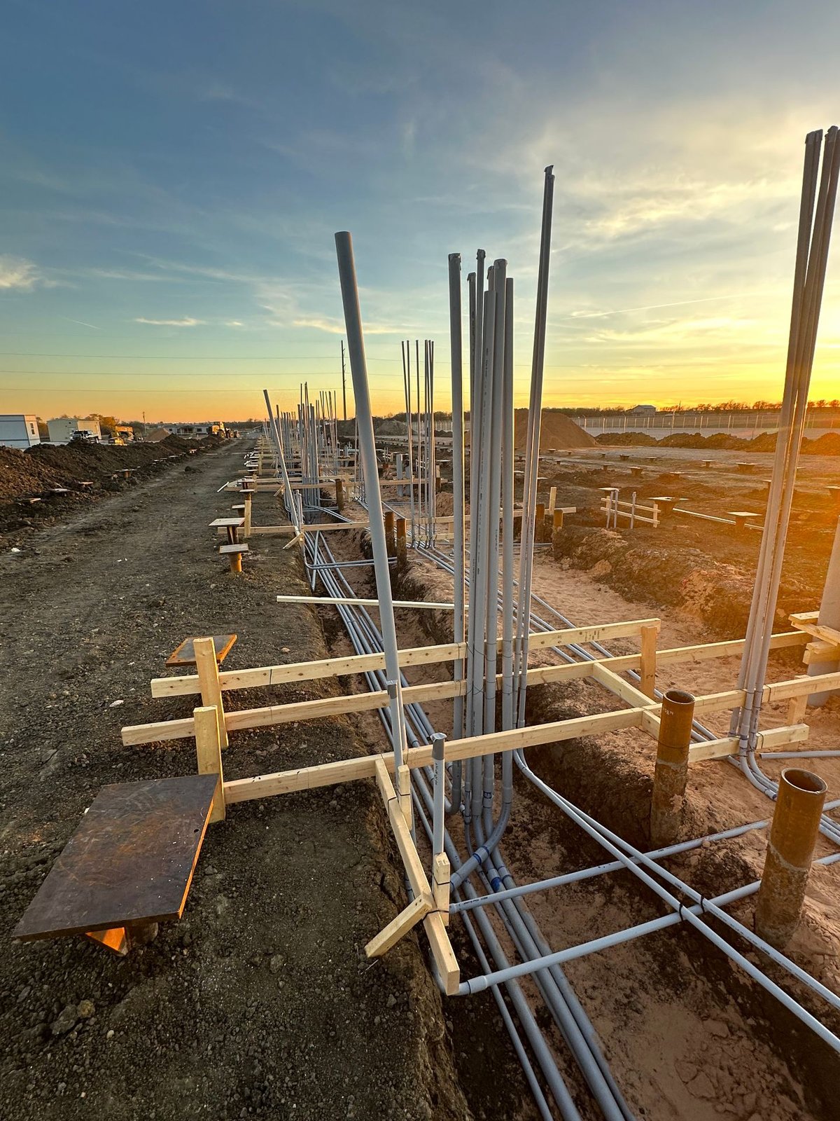 Underground conduit risers and rebar at utility-scale energy project at sunset