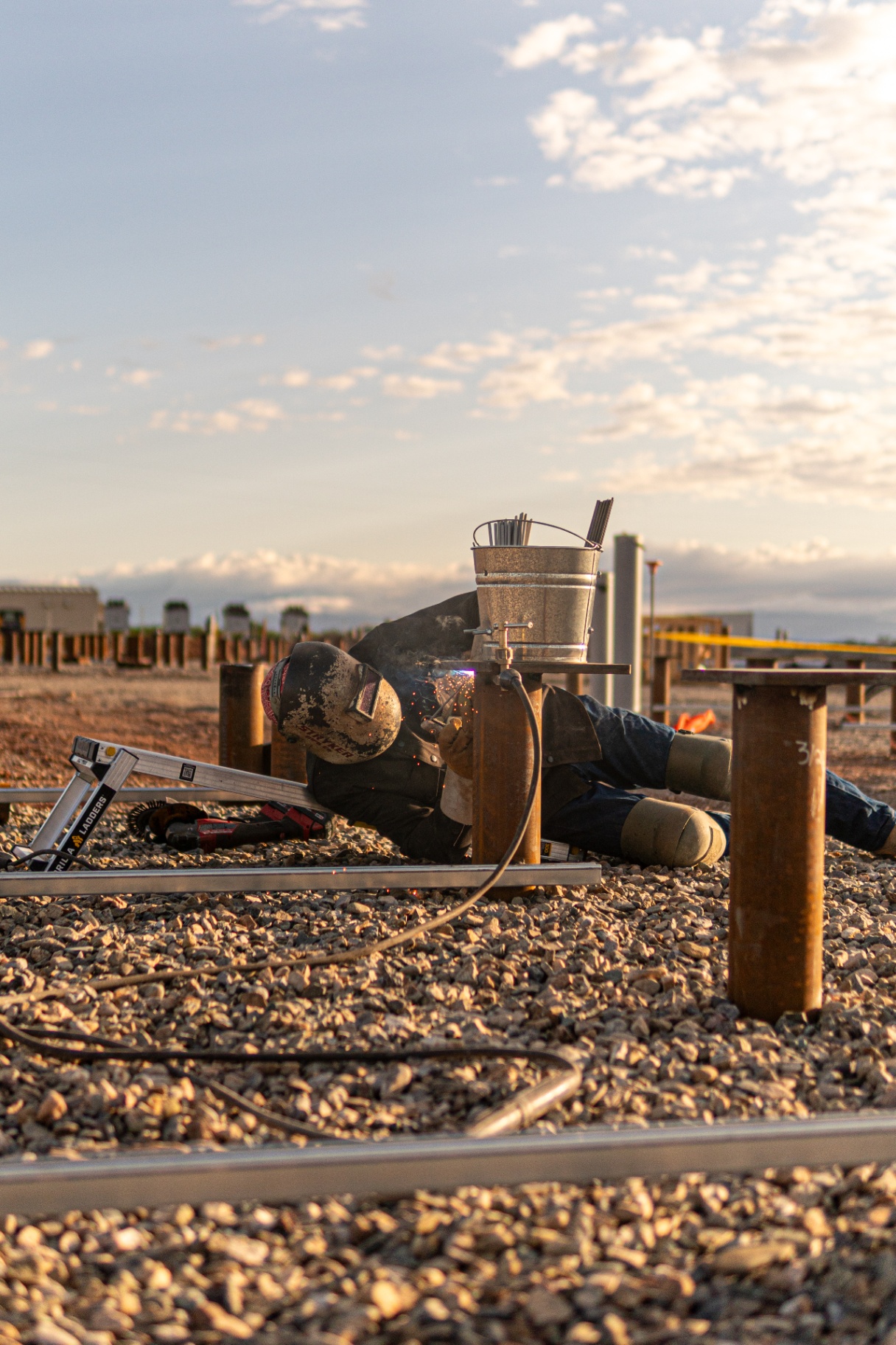 Field welder stick welding a pile cap on a BESS foundation site