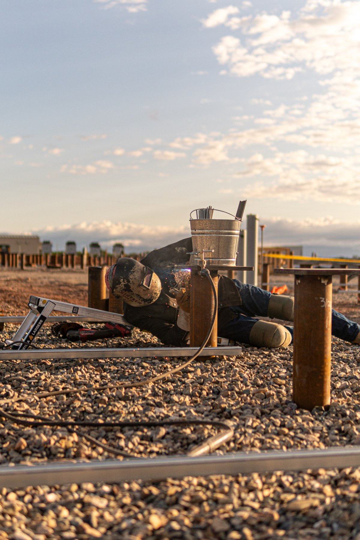 Field welder stick welding a pile cap on a BESS foundation site