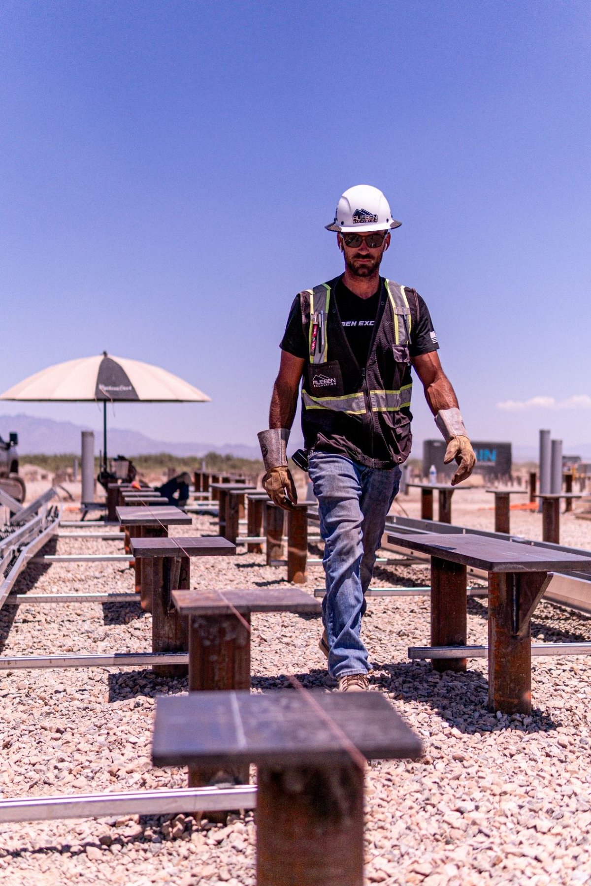 Rueben Excavation crew member walking a solar pile array on a desert jobsite