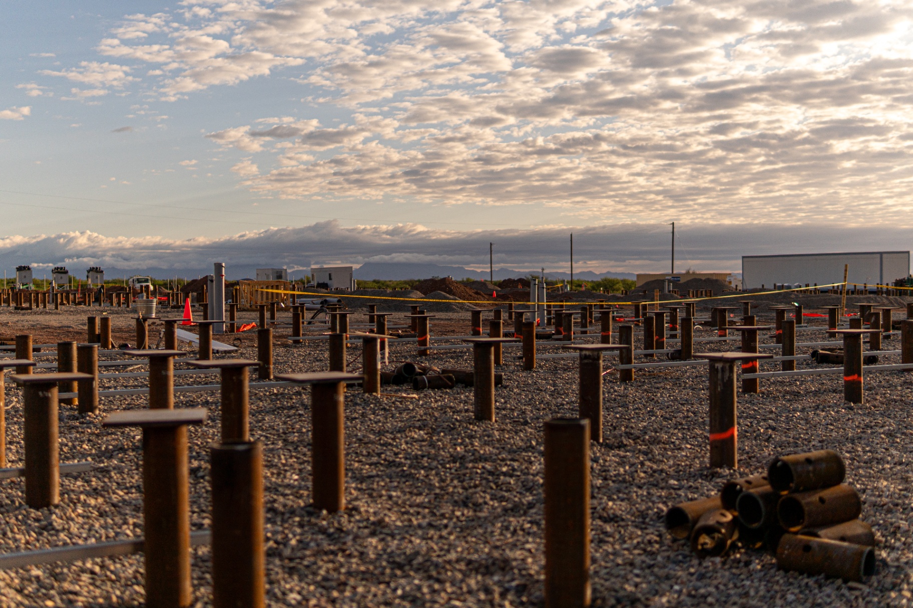 Field of installed helical piles at sunset on a utility-scale energy site