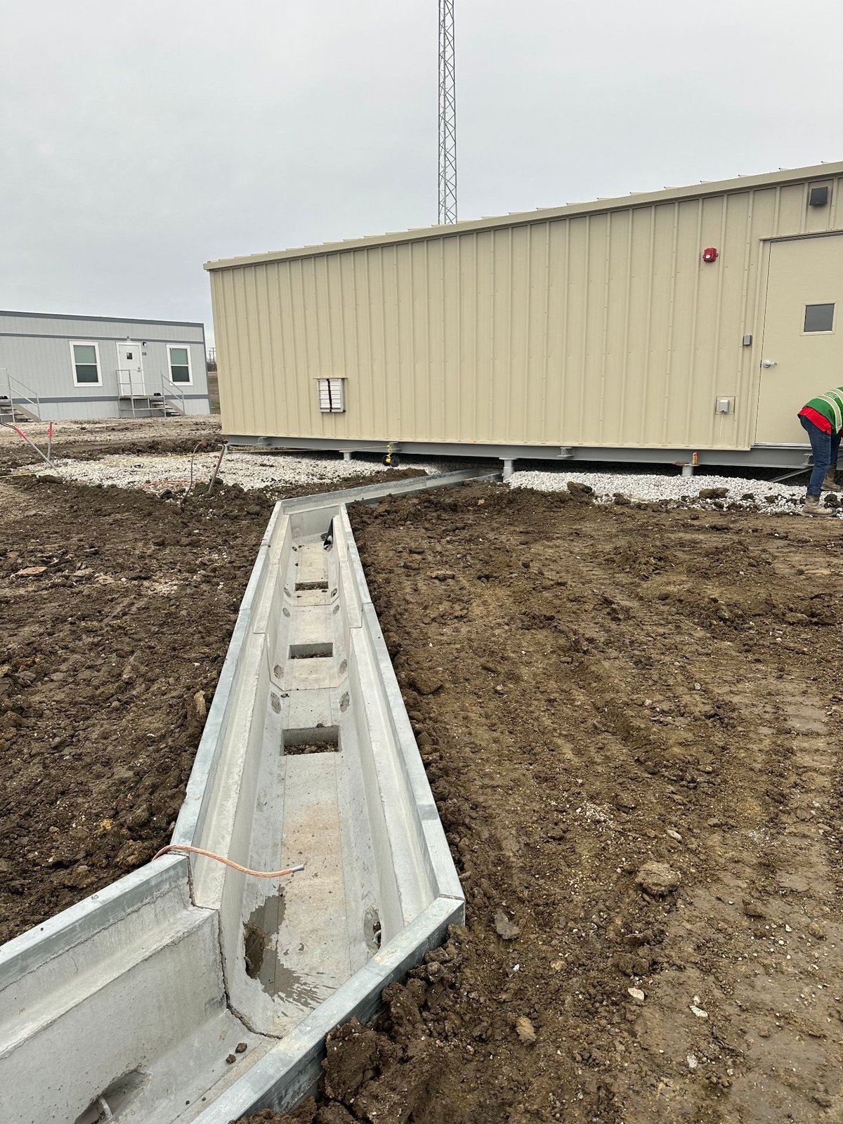 Galvanized cable trench routed to a prefabricated control house at a substation site
