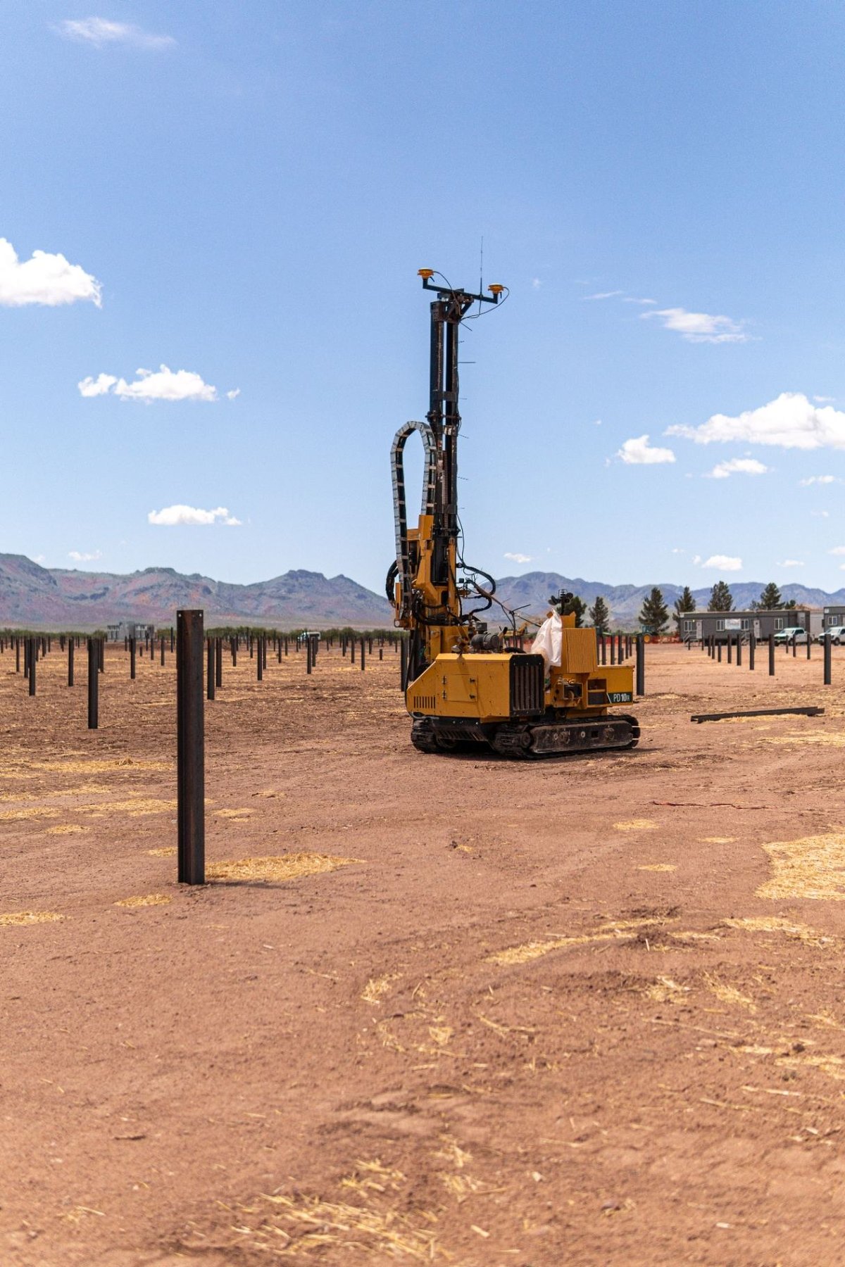 Driven pile rig installing steel piles in a desert solar field