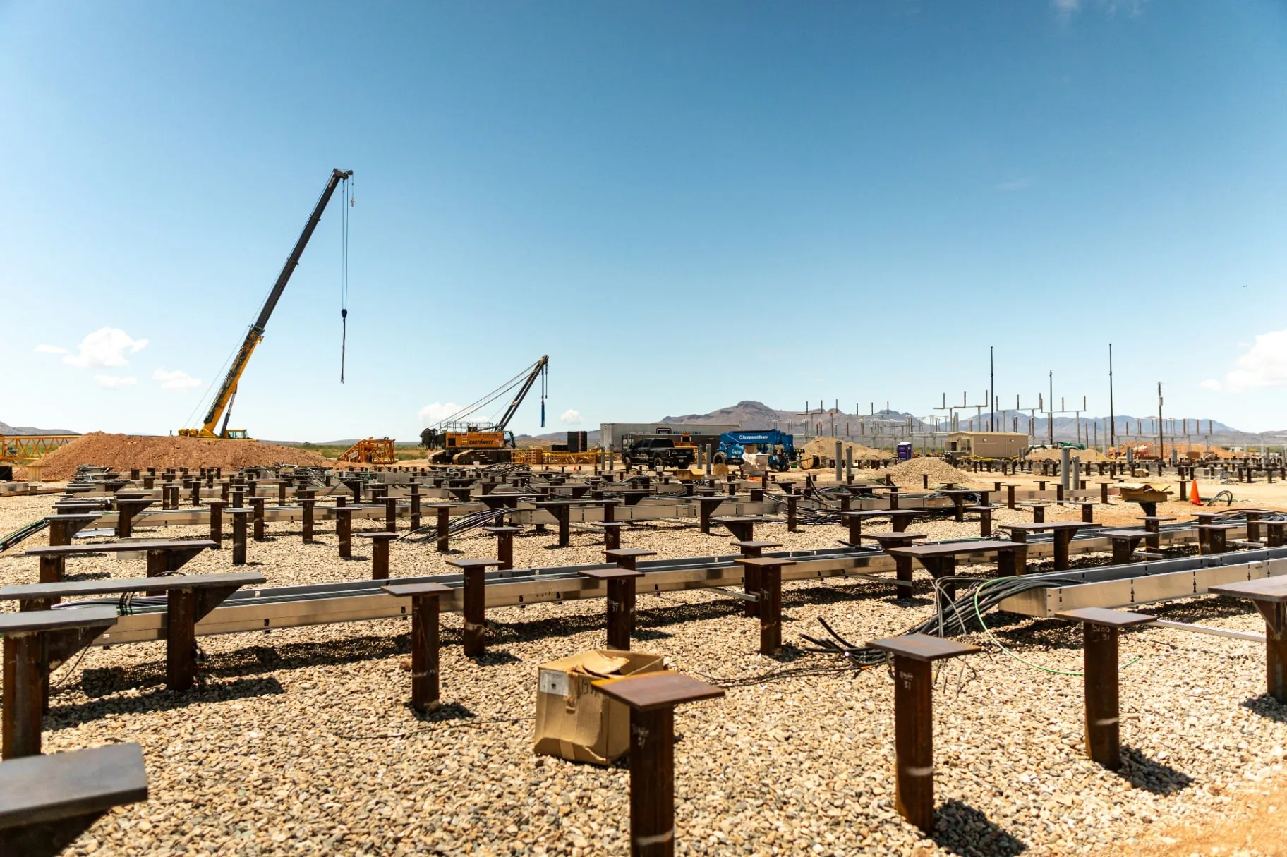 BESS pile cap foundation array with cranes and substation in the background